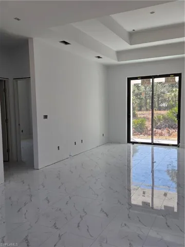 Unfurnished room featuring light marble finish floors and a raised ceiling