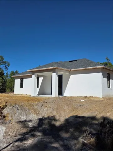 Back of property featuring stucco siding and roof with shingles