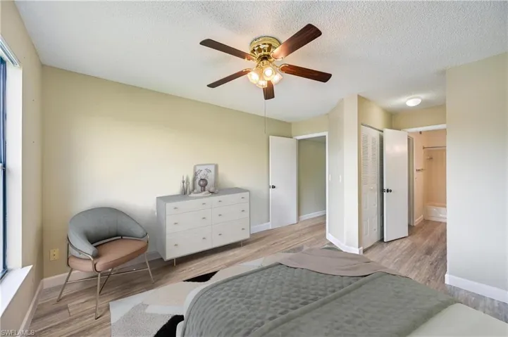 Bedroom featuring a textured ceiling, ensuite bath, ceiling fan, and light hardwood / wood-style flooring