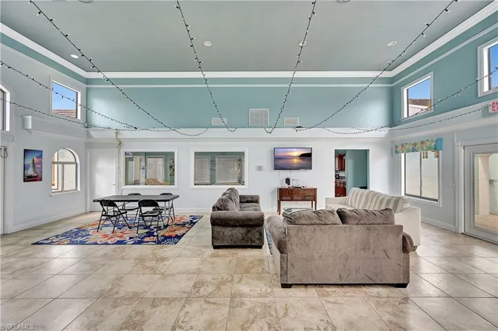 Living room featuring a towering ceiling, plenty of natural light, and ornamental molding