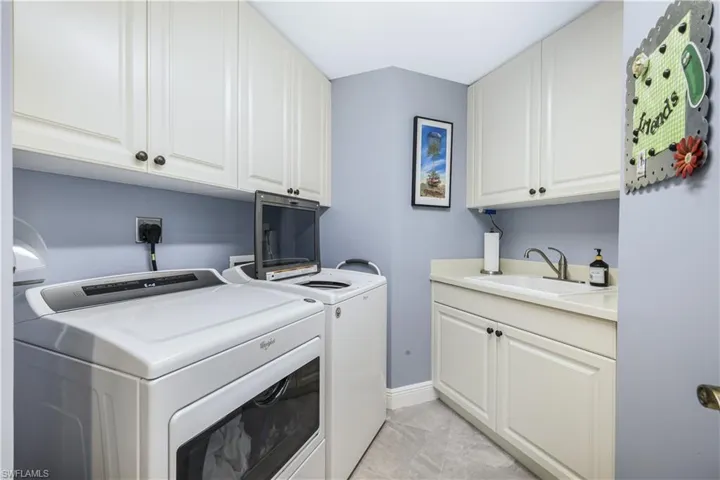Washroom featuring cabinet space, independent washer and dryer, and light tile patterned flooring