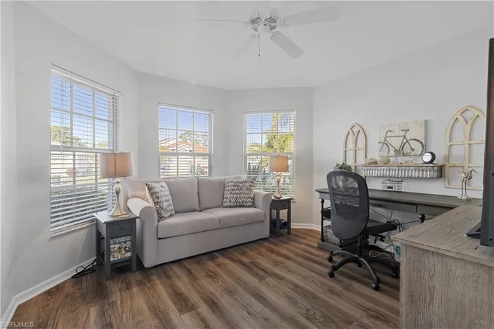 Office with dark wood-type flooring and ceiling fan