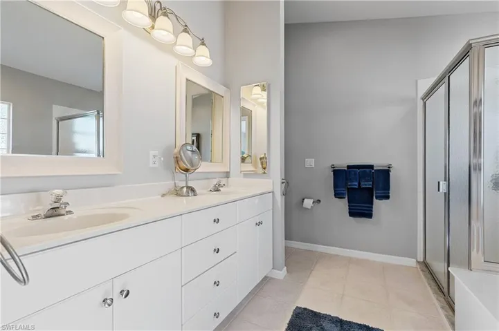 Bathroom with a shower with door, vanity, and tile patterned flooring
