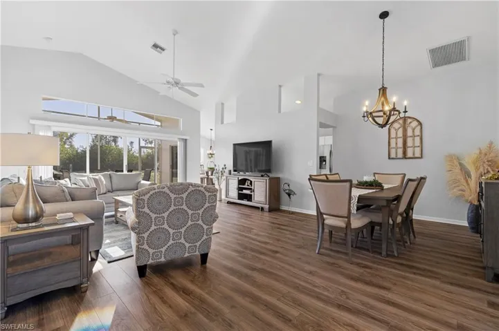Living room featuring ceiling fan with notable chandelier and dark hardwood / wood-style flooring