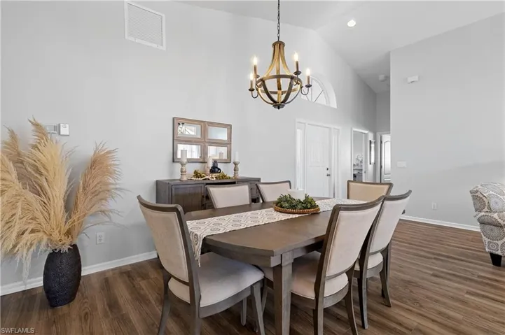 Dining space featuring a notable chandelier, high vaulted ceiling, and dark hardwood / wood-style floors