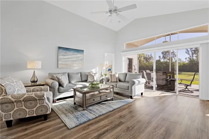 Living room featuring vaulted ceiling, wood-type flooring, and ceiling fan