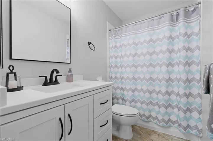 Bathroom featuring walk in shower, vanity, and toilet