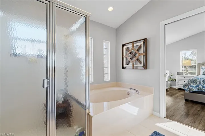 Bathroom with tile patterned flooring, lofted ceiling, and shower with separate bathtub