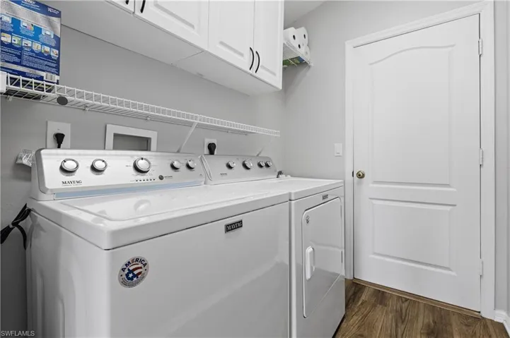 Clothes washing area featuring dark hardwood / wood-style flooring, cabinets, and washing machine and clothes dryer