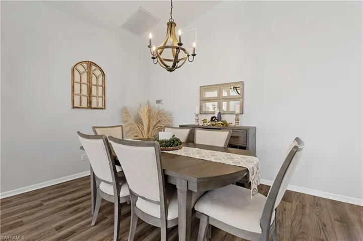 Dining area with vaulted ceiling, dark wood-type flooring, and an inviting chandelier