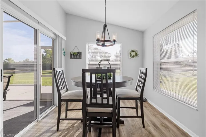Dining area with vaulted ceiling, hardwood / wood-style floors, and an inviting chandelier