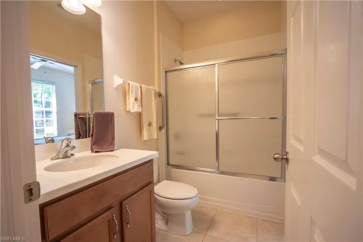 Bathroom featuring a wood-finish vanity with an integrated sink, satin nickel faucet, and overhead vanity lighting