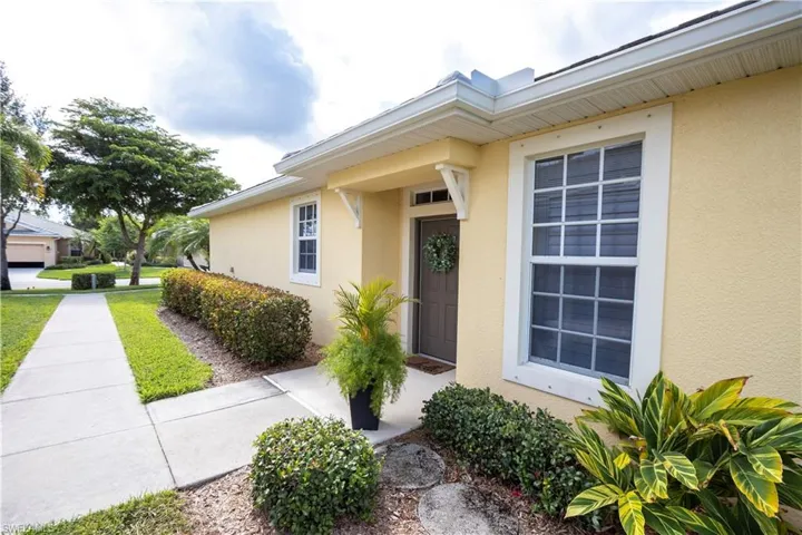 Stucco exterior with white trim, covered entryway, and front door with transom window