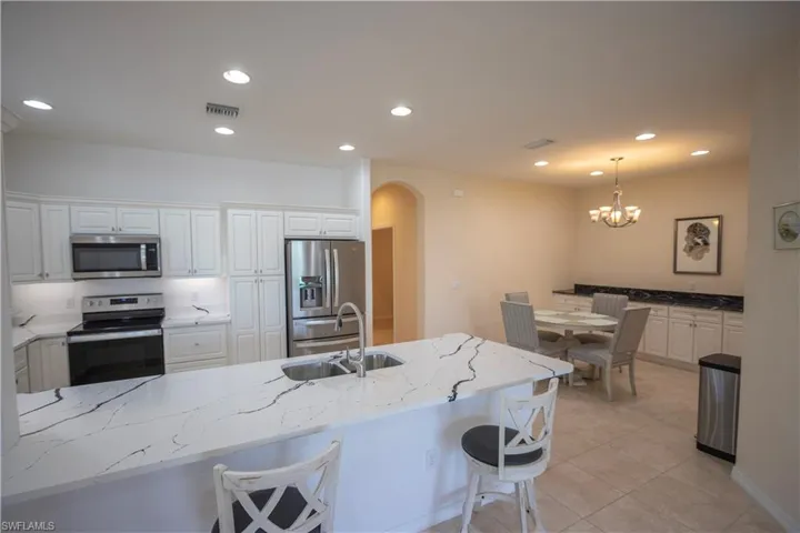 Kitchen featuring white cabinetry, stainless steel appliances, and a kitchen island with stone countertops