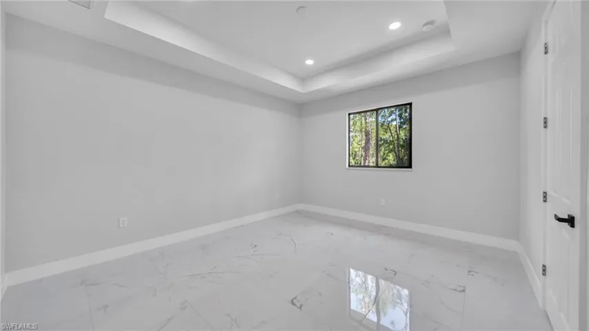 Spare room with light marble finish floors, a raised ceiling, and recessed lighting