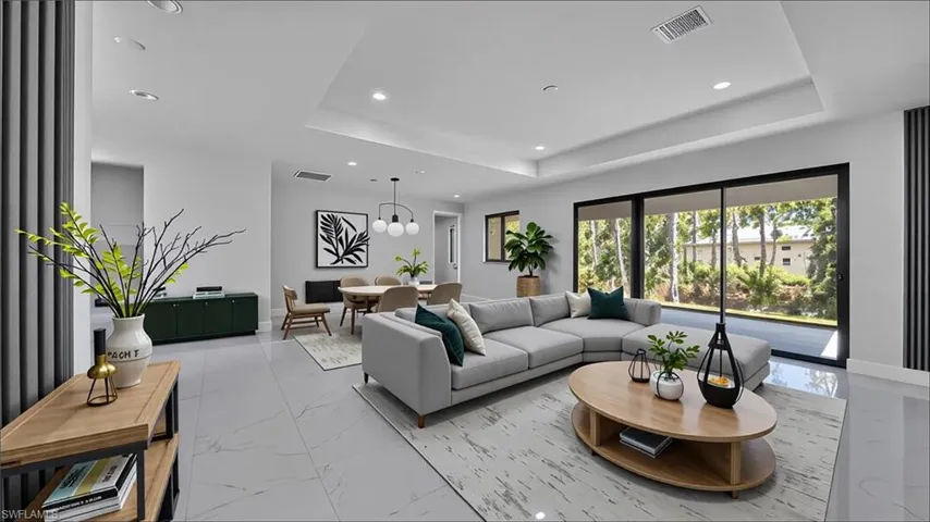 Living room with light marble finish floors, a raised ceiling, recessed lighting, and a chandelier