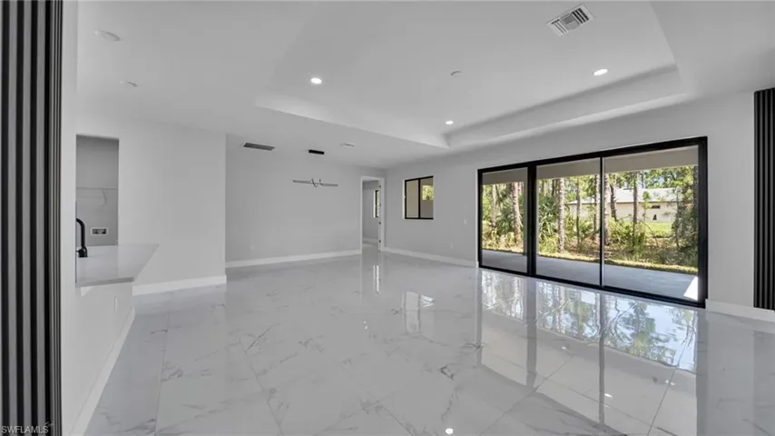 Spare room with light marble finish floors, a tray ceiling, and recessed lighting