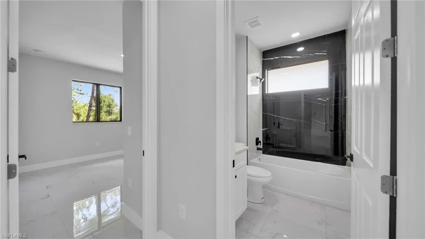 Full bath featuring marble finish floors, shower / tub combination, and vanity