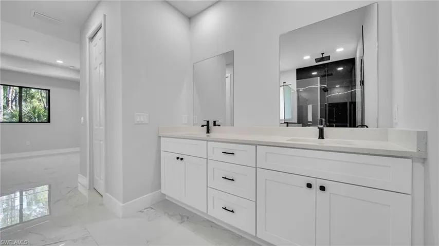 Full bathroom featuring marble finish flooring, double vanity, a marble finish shower, and recessed lighting