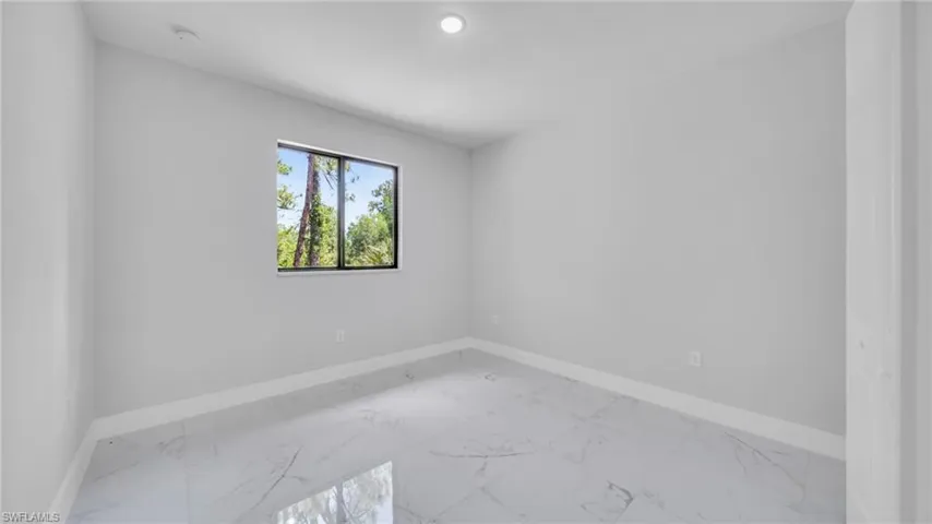 Empty room featuring light marble finish flooring and baseboards