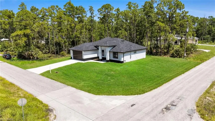 View of front of house with a garage, driveway, a front lawn, and a shingled roof