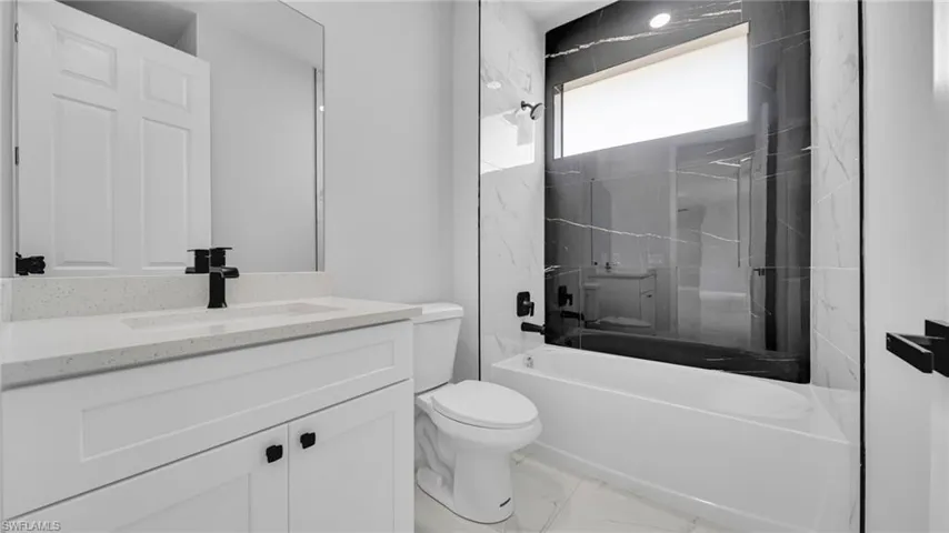Full bath with vanity, shower / bathtub combination, and marble look tiles