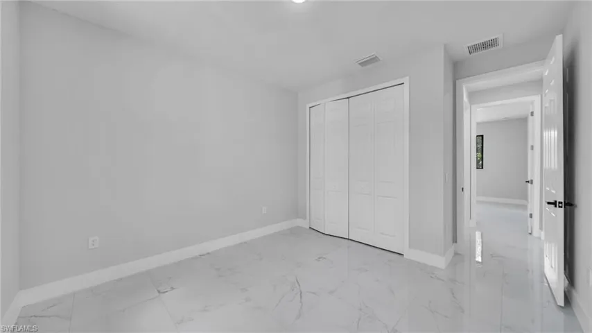 Unfurnished bedroom with light marble finish flooring and a closet