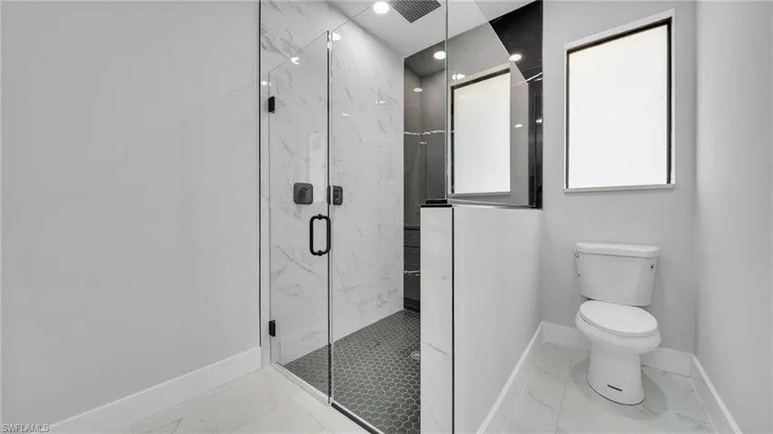 Full bathroom featuring marble look tile flooring and a marble finish shower