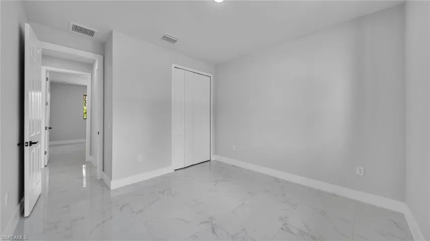 Unfurnished bedroom with light marble finish floors and a closet