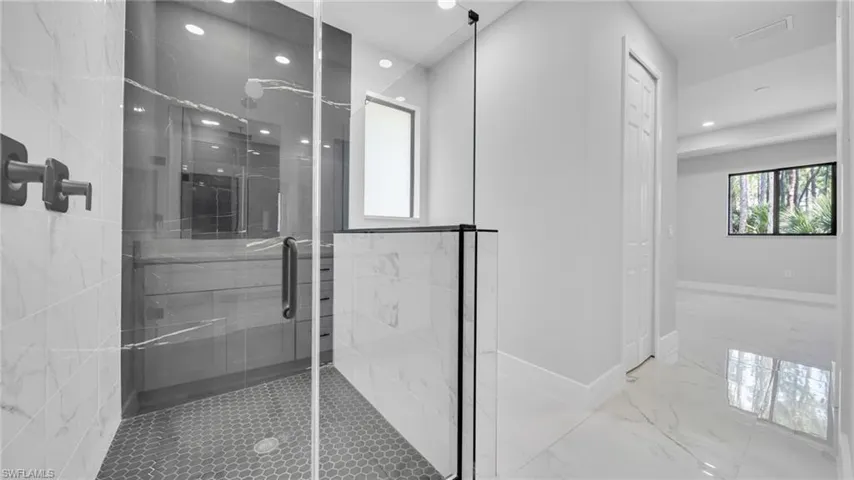 Bathroom featuring a shower stall, marble finish floors, and recessed lighting