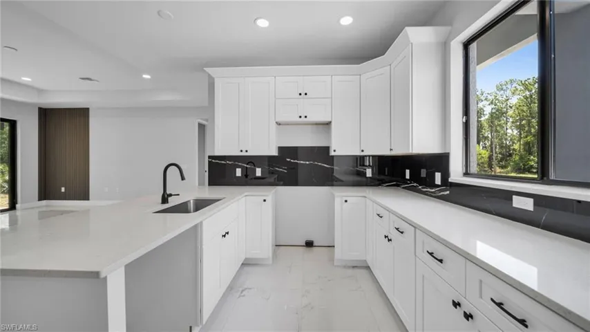 Kitchen featuring light marble finish flooring, recessed lighting, decorative backsplash, white cabinets, and light stone counters