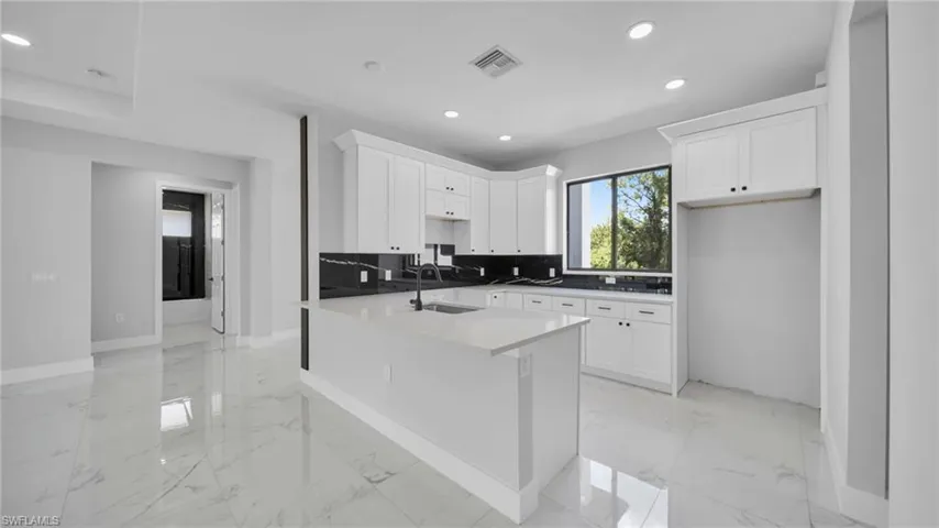 Kitchen with light marble finish floors, recessed lighting, white cabinets, and backsplash