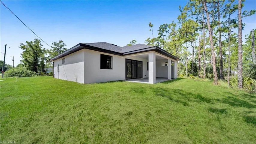 Rear view of property with a patio, a lawn, and stucco siding