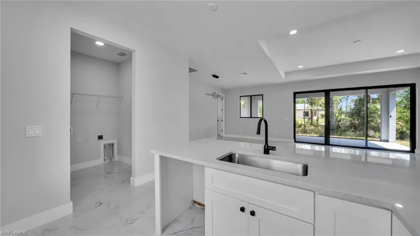 Kitchen with light marble finish flooring, white cabinets, recessed lighting, and light stone counters