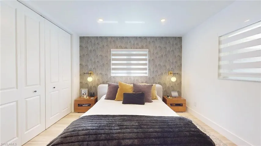 Bedroom with wood finished floors, wallpapered walls, baseboards, an accent wall, and recessed lighting