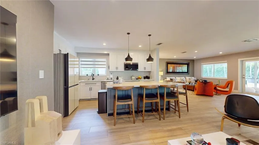 Kitchen featuring visible vents, a sink, open floor plan, white cabinets, and appliances with stainless steel finishes