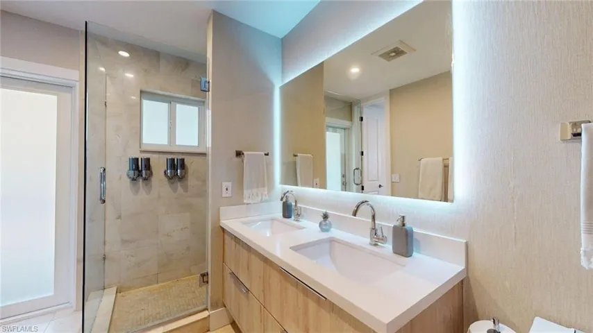 Bathroom featuring double vanity, a shower stall, and a sink