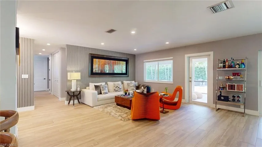 Living area featuring light wood finished floors, baseboards, visible vents, and recessed lighting