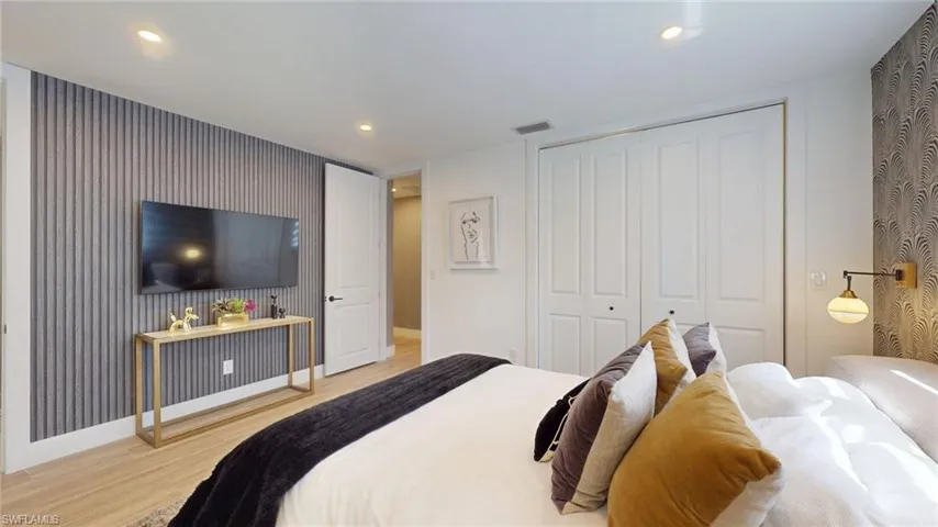 Bedroom with a closet, visible vents, wood finished floors, and baseboards