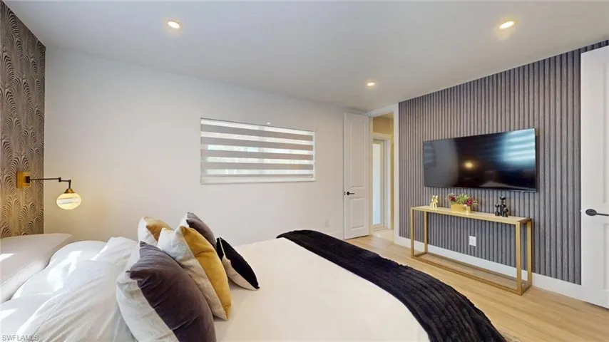 Bedroom with wallpapered walls, wood finished floors, baseboards, and recessed lighting