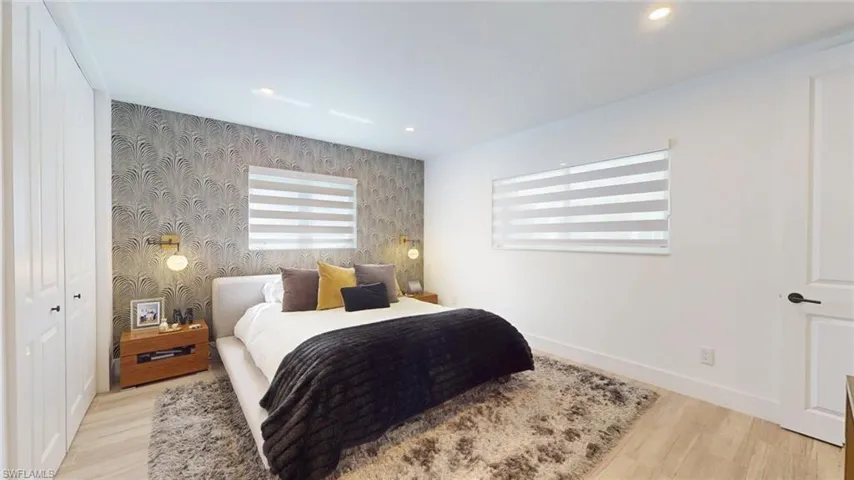 Bedroom featuring wood finished floors, wallpapered walls, baseboards, an accent wall, and recessed lighting