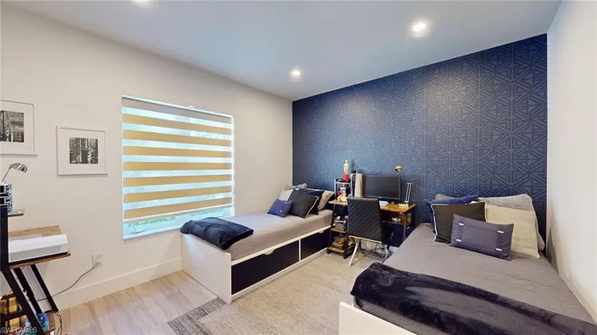 Bedroom with recessed lighting, wood finished floors, baseboards, and an accent wall