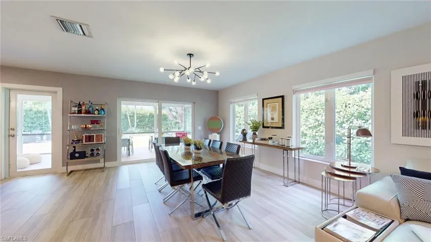Dining area featuring a wealth of natural light, light wood-style flooring, visible vents, and a chandelier