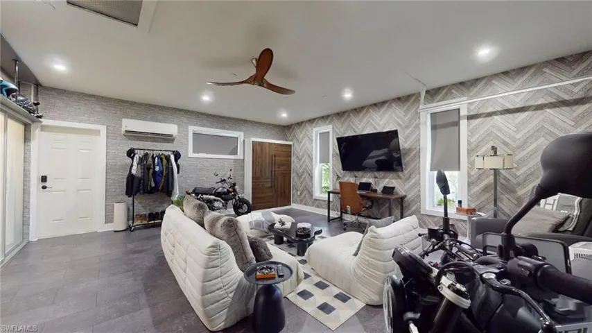 Living area featuring a ceiling fan, baseboards, a wall mounted air conditioner, and recessed lighting
