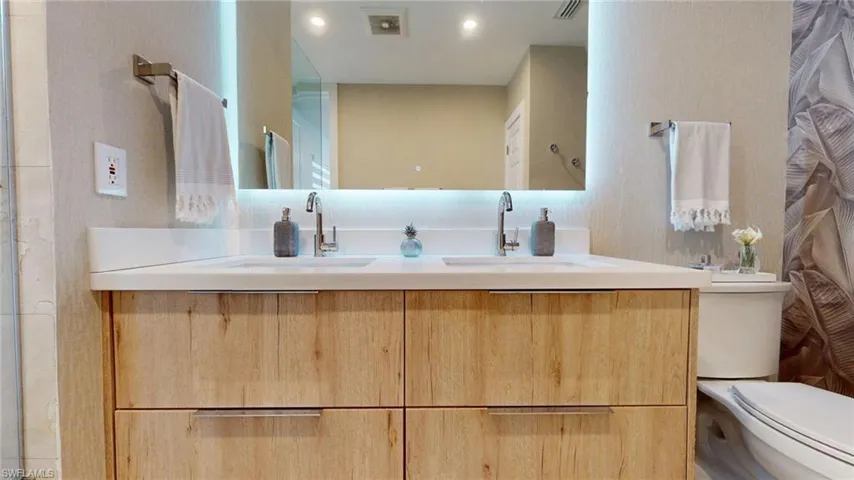 Bathroom with toilet, visible vents, a sink, and double vanity
