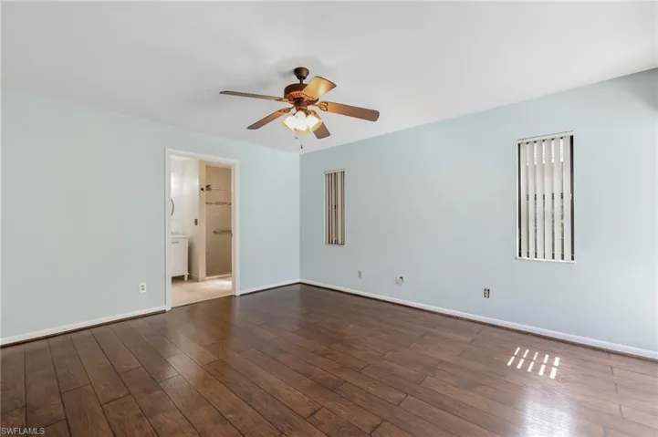 Spacious room featuring wood-finish flooring, a ceiling fan with integrated lighting, and light blue wall tones