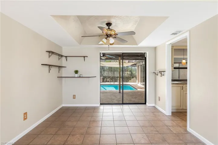 Dining area featuring a tray ceiling with a ceiling fan, tile flooring, and direct access to an outdoor pool area