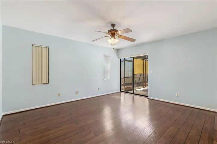 Spacious room featuring wood-finish flooring, a ceiling fan with integrated lighting, and light blue wall paint