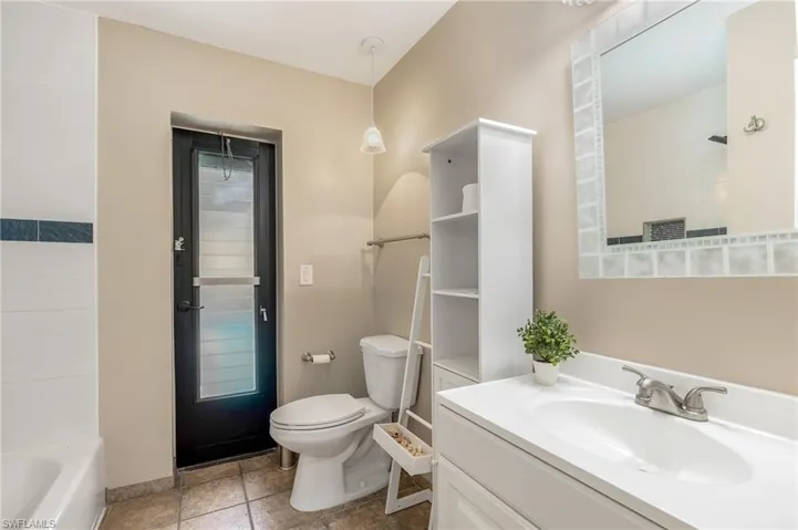 Bathroom featuring a white vanity with an integrated sink, a brushed nickel faucet, and a large mirror with a decorative tiled frame