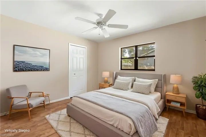 Virtually Staged - Bedroom with wood-finish flooring, a ceiling fan, and a window providing natural light